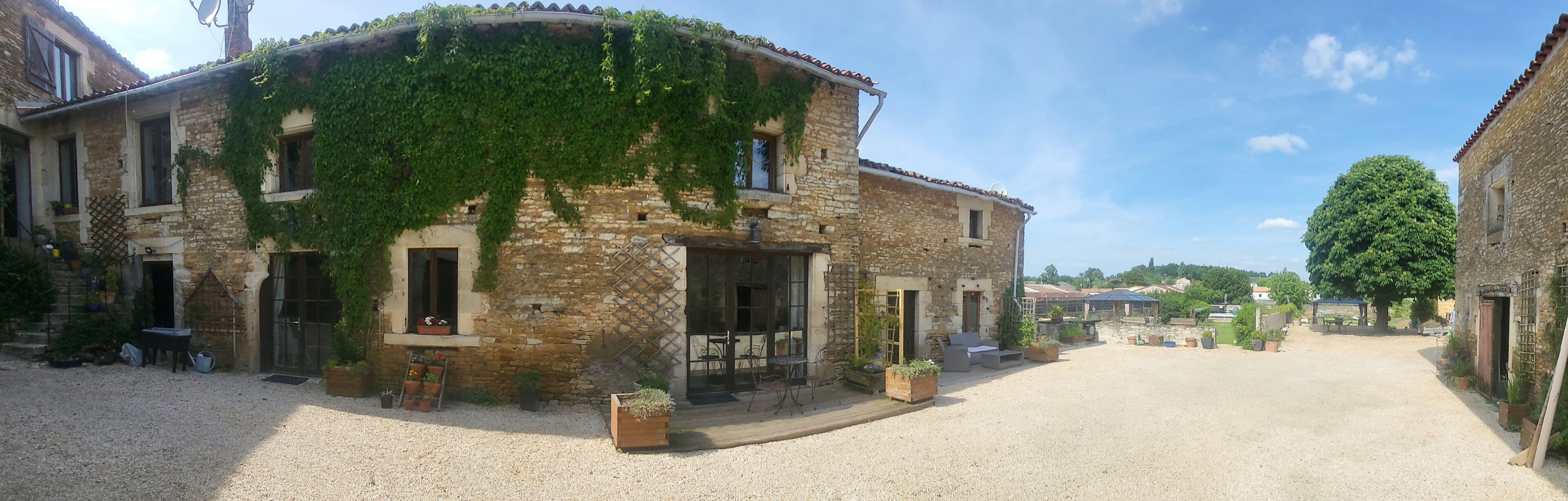 A stone building with ivy, outdoor seating, and a gravel courtyard.