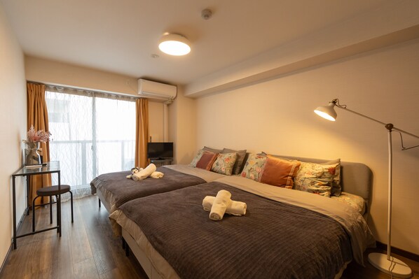 A hotel room with two beds, a desk with a chair, a TV, and a floor lamp. - The Premium Namba Minami (Osaka)
