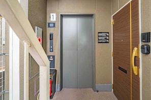 An elevator with a digital display, emergency call button, and a fire alarm. - Apartment Hotel 11 Namba Minami 7 (Osaka)