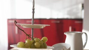 Un présentoir à trois niveaux avec des tasses et des soucoupes blanches, un pichet et une assiette de raisins.