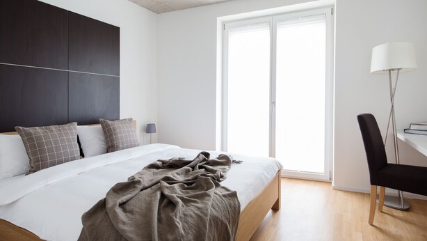 A modern bedroom with a bed, a desk, and a chair.