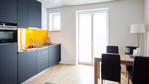 A modern kitchen with grey cabinets, a yellow backsplash, and a wooden dining table with black chairs.