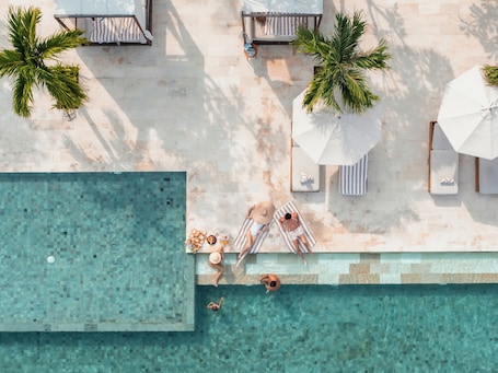 Una piscina al aire libre, sombrillas, sillones reclinables de piscina. Cocana Resort Gili Trawangan
