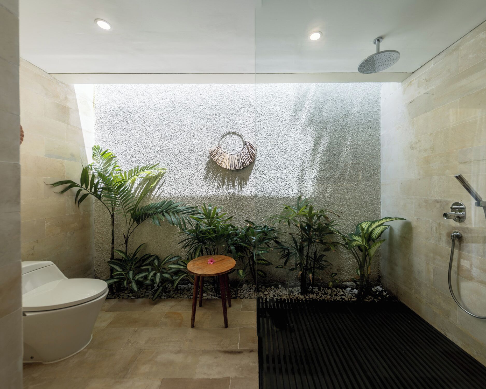 A bathroom with a shower, toilet, and a small table with a plant.