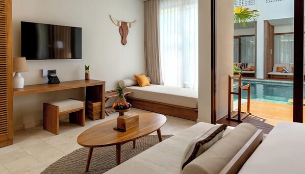 Habitación de hotel moderna con televisor de pantalla plana, una mesita de madera, un sofá y vistas a una piscina al aire libre.