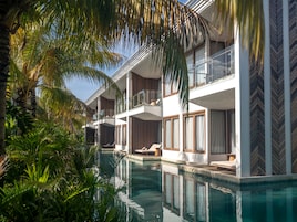 Un hotel moderno con piscina, balcones y abundante vegetación.