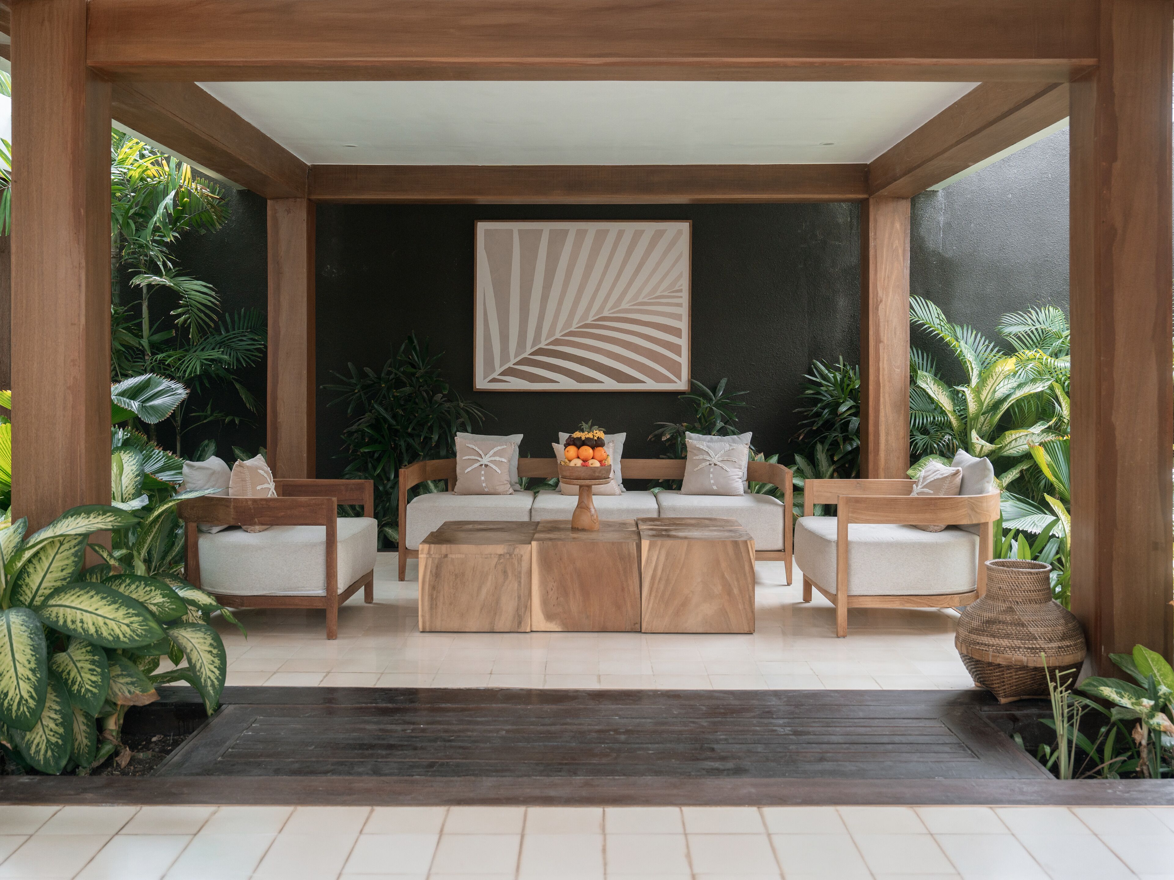 Un espace extérieur moderne aménagé avec un ensemble de canapés, une table basse en bois et un saladier décoratif rempli de fruits.