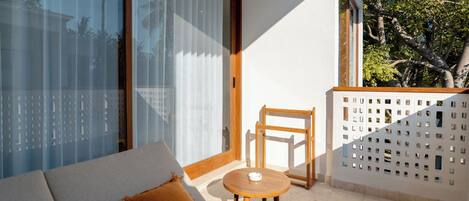 Un balcon avec un canapé, une petite table et une chaise.