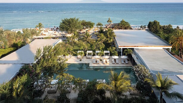 A resort with a swimming pool, lounge chairs, and a view of the ocean and a mountain. - Cocana Resort Gili Trawangan (Gili Trawangan)