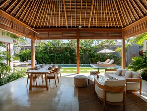 Un espacio al aire libre techado con piscina, sillones de descanso y una zona de comedor.