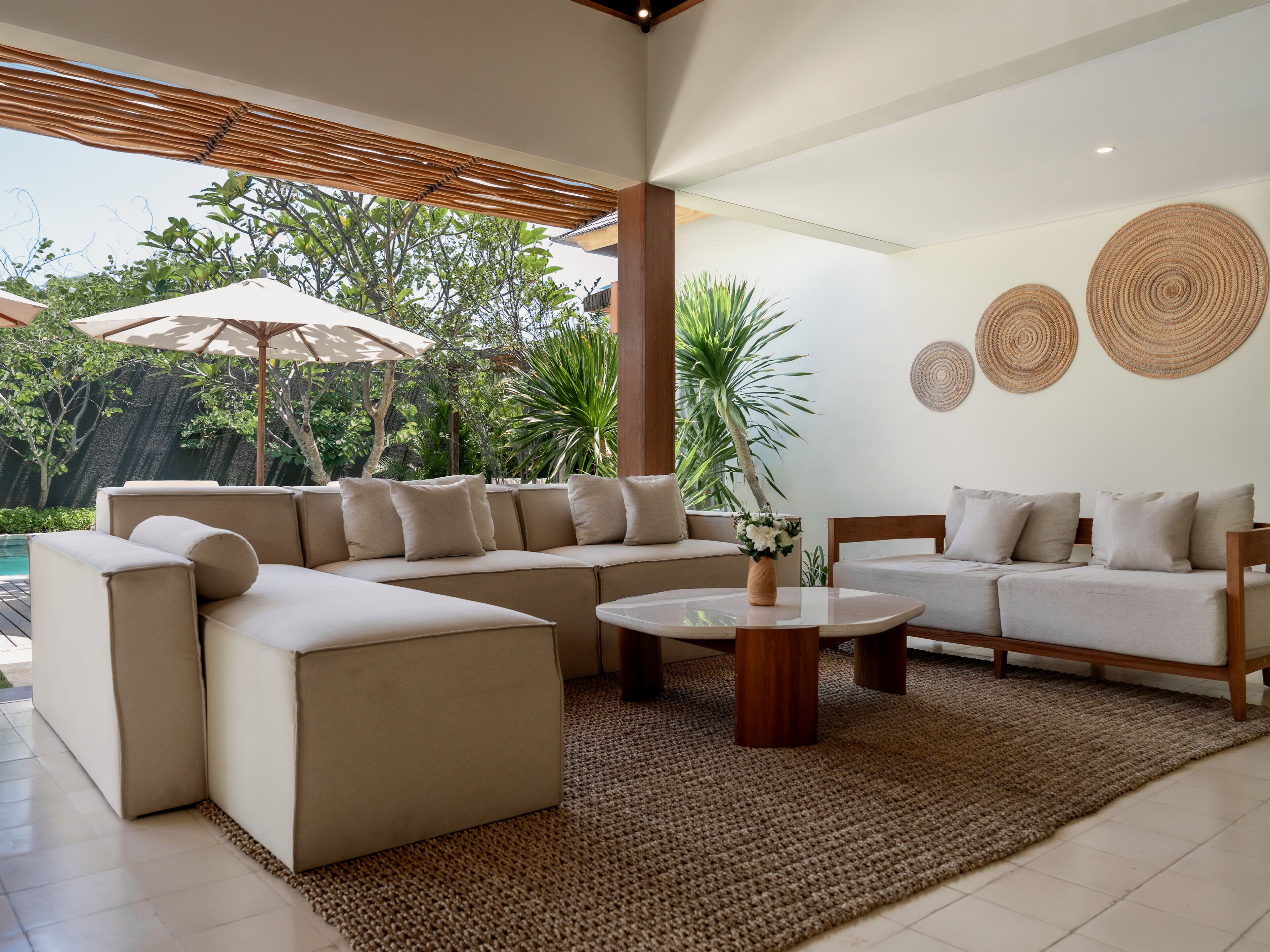 A modern living room with a sectional sofa, a coffee table, and a large umbrella.