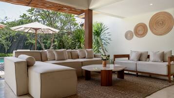 A modern living room with a sectional sofa, a coffee table, and a large umbrella.