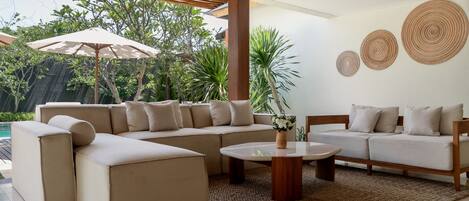 A modern living room with a sectional sofa, a coffee table, and a large umbrella.