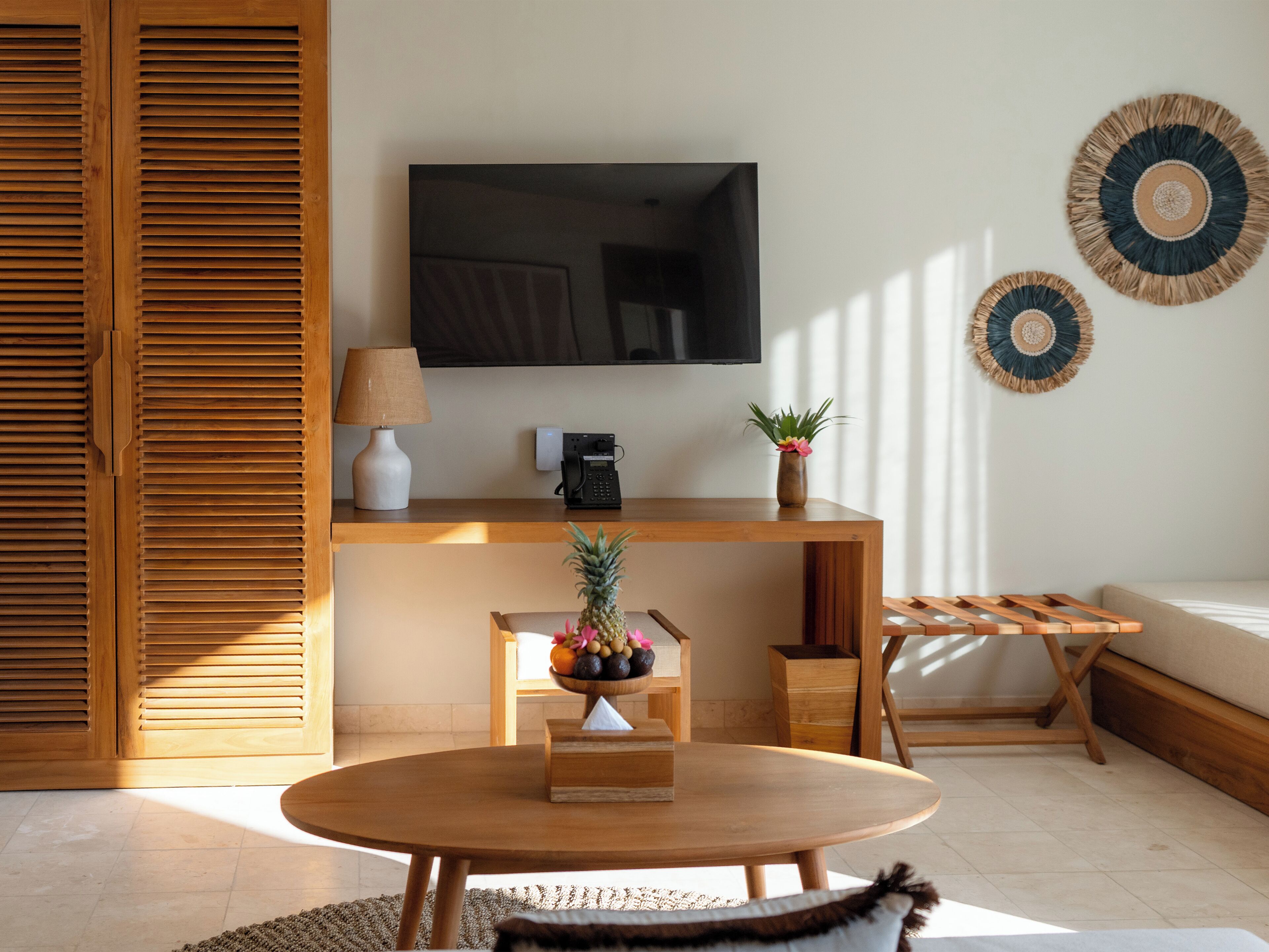 Uma sala de estar moderna com uma mesa de madeira, um sofá, uma TV e um telefone fixado na parede.