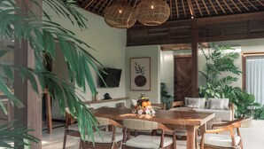 A dining area with a wooden table and chairs, surrounded by potted plants. - Cocana Resort Gili Trawangan (Gili Trawangan)