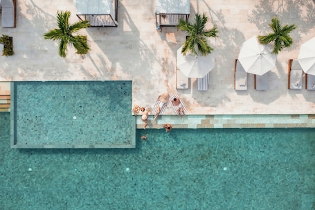 Una piscina al aire libre, sombrillas, sillones reclinables de piscina
