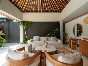 Una sala de estar moderna con techo de madera, un sofá, una mesa de centro y un comedor con sillas y una mesa.