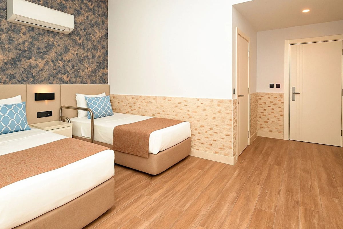 A hotel room with two beds, a bathroom, and a door.