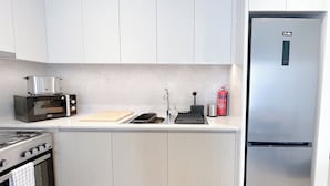 A modern kitchen with white cabinets, a stainless steel refrigerator, a built-in oven, a microwave, and a toaster. - Incredible stay at Burj Royale Downtown (Dubai)