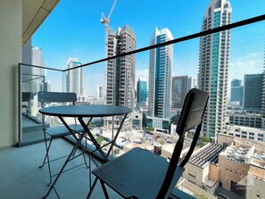 Een balkon met een tafel en stoelen, met uitzicht op een stadsgezicht met hoogbouw en hoogwerkerkranen.
