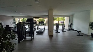 Un gimnasio espacioso con diversos equipos de ejercicio, amplias ventanas y un diseño moderno y limpio.