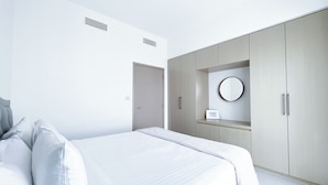 Un dormitorio moderno con cama, armario y espejo.