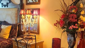 A dining area with a round table, chairs, a vase with flowers, and wall-mounted decor. - Cozy Victorian apartment, best view in Lake Las Vegas Resort and golf course. (Henderson)