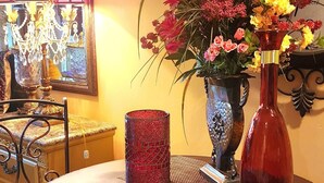 A round table with a woven placemat, a red vase, and a floral arrangement. - Cozy Victorian apartment, best view in Lake Las Vegas Resort and golf course. (Henderson)