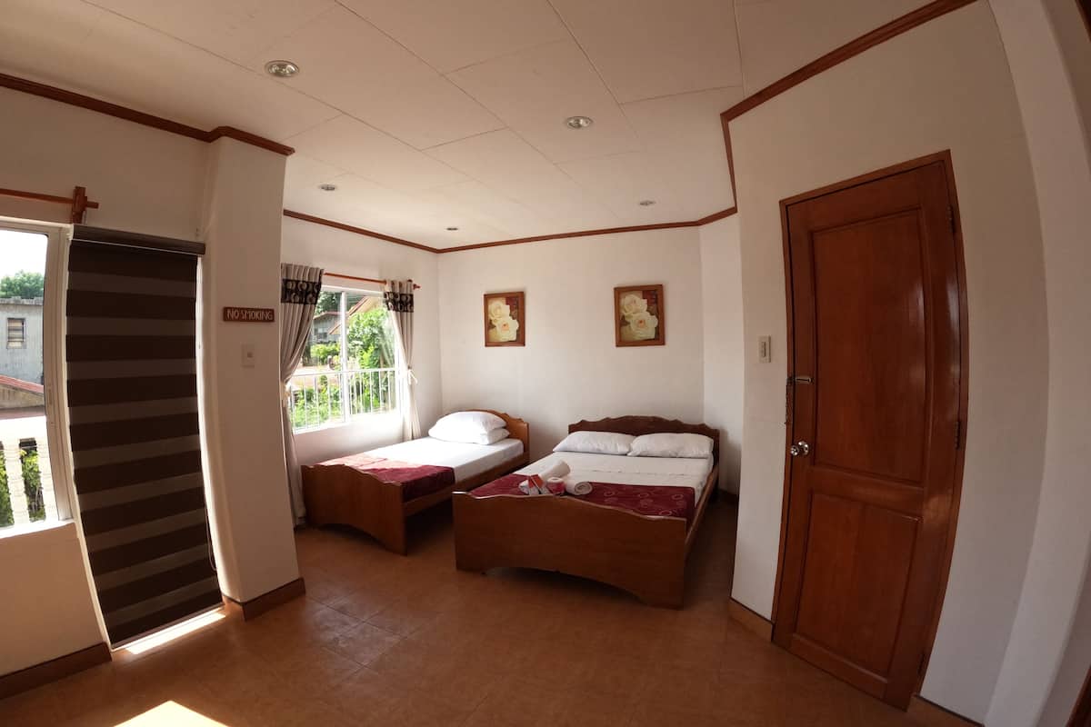 Una habitación con dos camas, una puerta corredera y una ventana con cortinas.