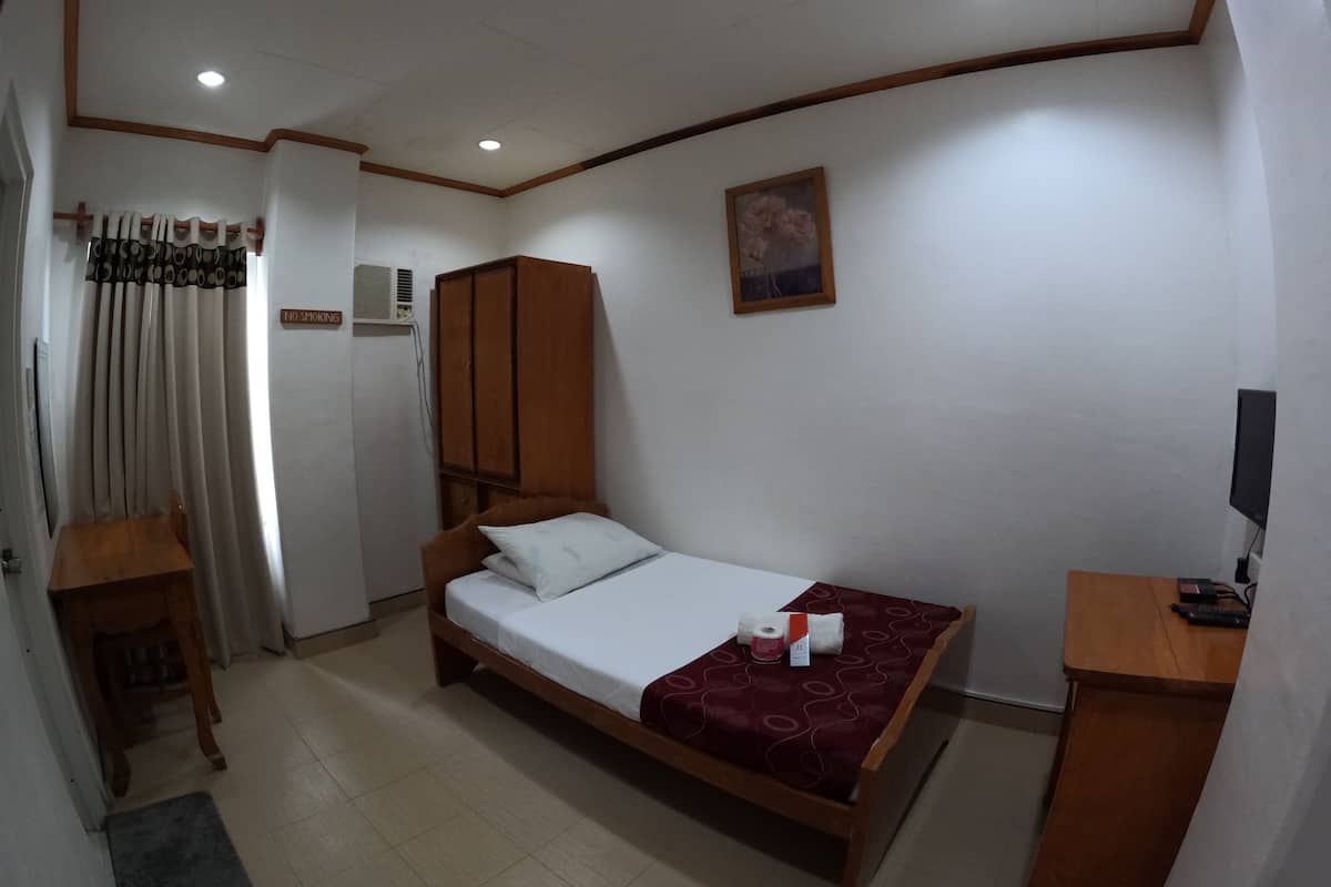 Un dormitorio con una cama individual, un armario de madera, un escritorio y un televisor.