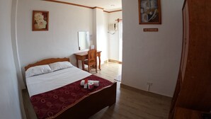 Una camera d'albergo con un letto, una scrivania, una sedia e un quadro appeso al muro.