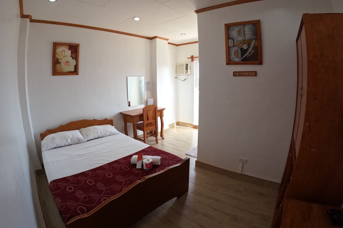 Una habitación de hotel con una cama, un escritorio, una silla y un cuadro en la pared.