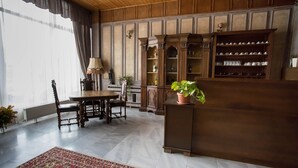 Habitación tradicional con techo de madera, una zona de comedor con mesa y sillas, un mueble grande con estantes y una planta en maceta.