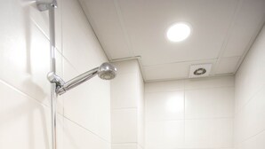 Un baño pequeño y moderno con ducha, inodoro y soporte para papel higiénico.