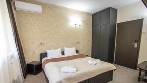 Una habitación de hotel con cama, armario, mesita de noche y una silla.