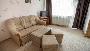 Una sala de estar con un sofá, una mesa de centro y un televisor sobre un mueble de madera.