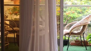 Ein Zimmer mit einer Schiebetür zum Balkon, der Korbmöbel und Blumentöpfe bietet.