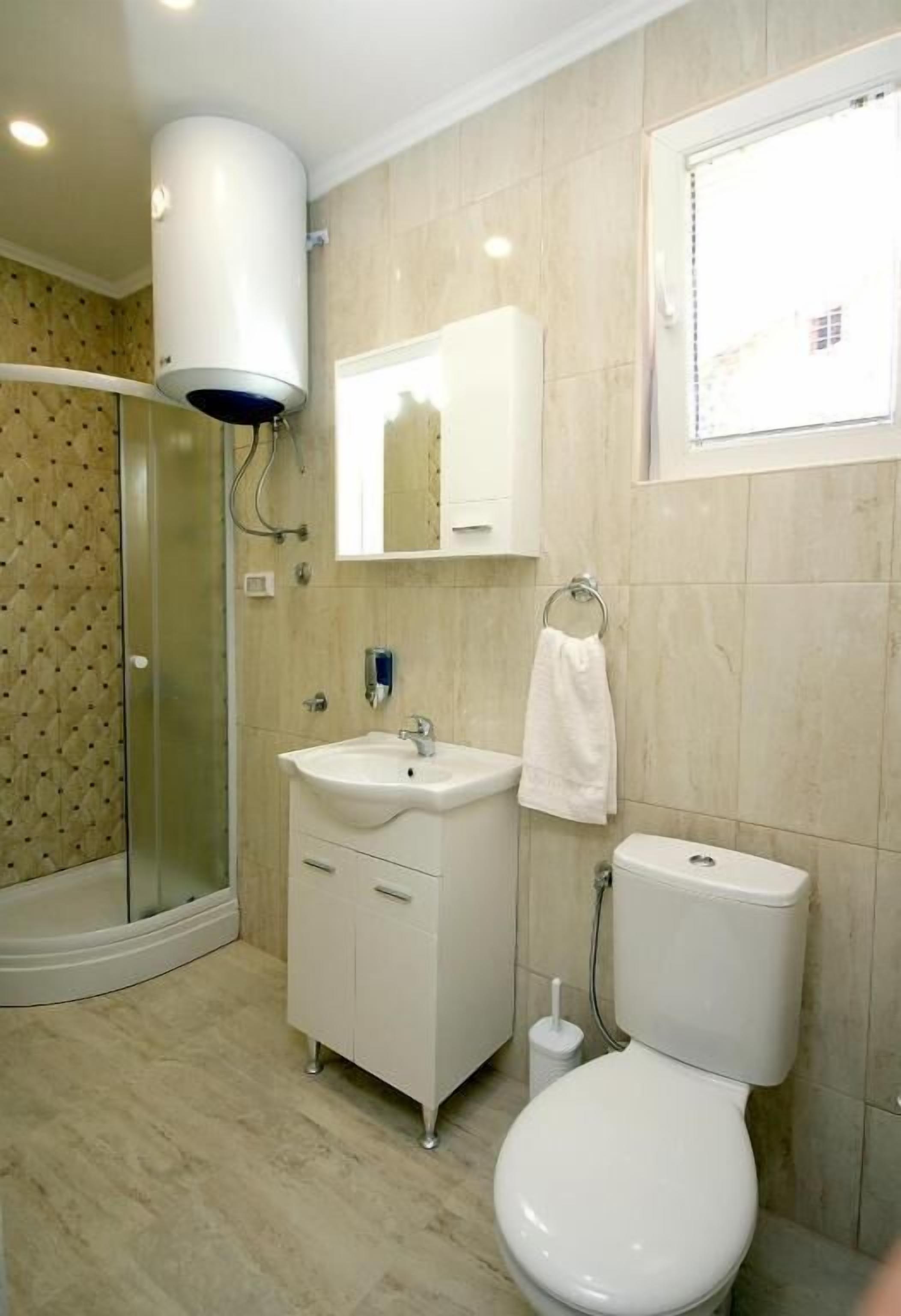 Un baño con cabina de ducha de vidrio, un lavabo blanco, un inodoro y un espejo sobre el lavabo.
