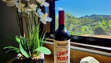 A bottle of wine, a potted plant, and a window with a view of a landscape.