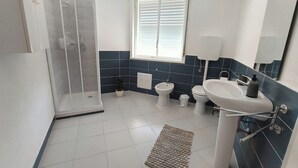 Un baño moderno con ducha, inodoro, bidé y lavabo.