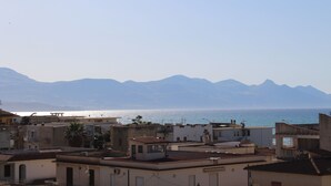 Un pueblo costero con edificios que dominan el mar y montañas al fondo.