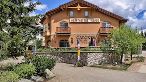 A building with a sign reading "HEARTHSTONE LODGE" and "CAPONES ITALIAN CHEEN". - Hearthstone Lodge #422 (Sun Peaks)