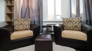 A modern living room with two dark leather sofas, patterned cushions, a small round table, and a bookshelf. - 2-bed, 1.5-bath Old Town Flat with Sauna and Bar (Tallinn)