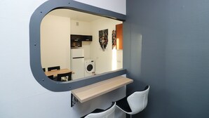 A compact room with a round mirror, a wooden bench, a washing machine, and a small table. - 2-bed, 1.5-bath Old Town Flat with Sauna and Bar (Tallinn)