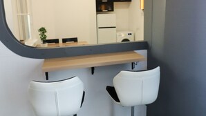 A modern bathroom with a large mirror, two white bar stools, and a wooden countertop. - 2-bed, 1.5-bath Old Town Flat with Sauna and Bar (Tallinn)
