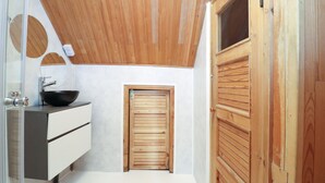 A modern bathroom with a wooden ceiling, a sink with a black basin, and a white cabinet. - 2-bed, 1.5-bath Old Town Flat with Sauna and Bar (Tallinn)