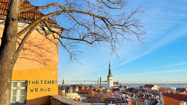 A historic building with a sign reading "THE TIMES WE HAD" overlooking a town with traditional architecture and a prominent church spire. - 2-bed, 1.5-bath Old Town Flat with Sauna and Bar (Tallinn)