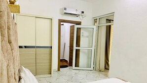 Une chambre d’hôtel avec un lit, une armoire, une salle de bain avec un miroir et une fenêtre avec des rideaux.