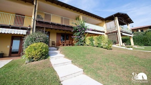 A two-story building with a balcony, a covered patio, and a well-maintained lawn.