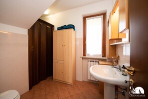Ein Badezimmer mit Toilette, Holzschrank und Waschbecken mit Spiegel darüber.